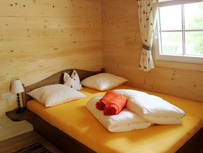 Luxuscamping - TV - Ferienhütte "Drachenwand": Schlafzimmer mit Doppelbett - CAMP MondSeeLand Ferienhütten am CAMP MondSeeLand