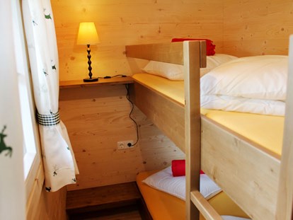Luxuscamping - TV - Ferienhütte "Drachenwand": Kinderzimmer mit einem Stockbett - CAMP MondSeeLand Ferienhütten am CAMP MondSeeLand