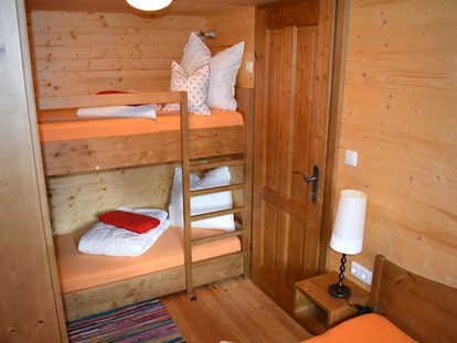Luxuscamping - TV - Ferienhütte "Schober": Schlafzimmer mit Doppelbett und einem Stockbett - CAMP MondSeeLand Ferienhütten am CAMP MondSeeLand