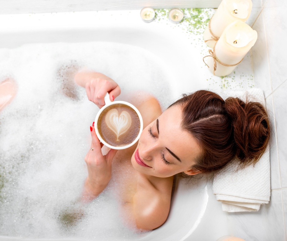 Woman lying in the bathtub with a coffee cup