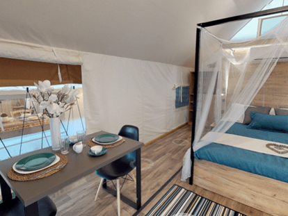 Luxuscamping - WC - Savinjska - Lakeside romantic Tent Schlafzimmer mit Doppelbett und der Sitz- bzw. Essbereich - Lakeside Petzen Glamping Resort Lakeside romantic Tent im Lakeside Petzen Glamping Resort
