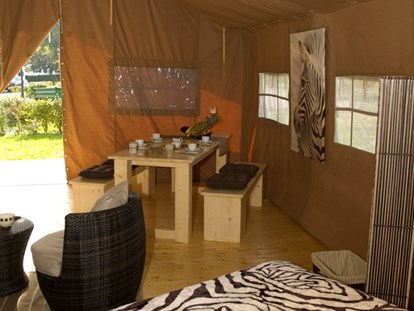 Luxuscamping - Gartenmöbel - Region Schwaben - Blick vom Safarizelt auf die Terrasse. Dort gibt es ebenfalls einen langen Tisch und Bänke - für ein Abendessen bei Sonnenuntergang. - Camping Park Gohren Safarizelte Camping Park Gohren