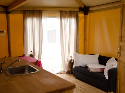 Luxuscamping - barrierefreier Zugang - Venedig - Glamping-Zelte: Wohnzimmer mit Tisch, Stühlen, Spülbecken, Kühlschrank (ohne Küche) und Schlafsofa - Camping Rialto Glampingzelte auf Camping Rialto