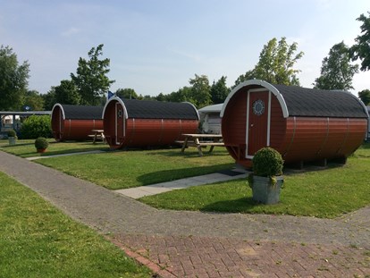 Luxuscamping - WC - Ostfriesland - Camping-Schlaffässer am See. Die Fässer stehen in exklusiver Lage direkt am Badesee mit Blick aufs Wasser. - Freizeitpark "Am Emsdeich" Schlaffass mit Seeblick auf dem Freizeitpark "Am Emsdeich"