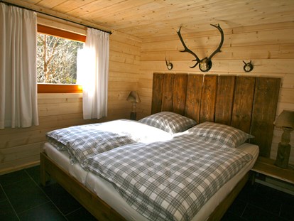 Luxuscamping - Parkplatz bei Unterkunft - Jagdhütte - Schlafzimmer mit Doppelbett - Camping Langenwald Blockhäuser auf Camping Langenwald