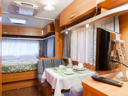 Luxuscamping - TV - Cavallino - Wohnzimmer und Doppelbett - Camping Ca' Pasquali Village Caravan Pinienwald auf Camping Ca' Pasquali Village