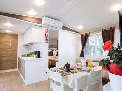Luxuscamping - Sonnenliegen - Venedig - Wohnzimmer mit Küche und im unteren Schlafzimmer der Kinder - Camping Vela Blu Mobilheim Top Residence Platinum auf Camping Vela Blu