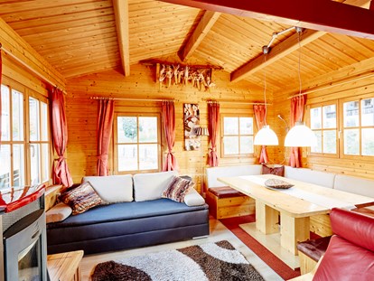 Luxuscamping - Preisniveau: günstig - Ried (Arzl im Pitztal) - Wohnbereich mit gemütlicher Sitzecke Pelletsofen, ausziehbarer Couch - Camping Dreiländereck in Tirol Blockhütte Tirol Camping Dreiländereck Tirol