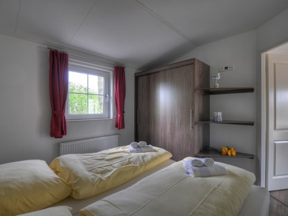Luxuscamping - TV - Region Fehmarn - Das Schlafzimmer mit Doppelbett. - Camping- und Ferienpark Wulfener Hals Ferienhaus Seemöwe 4 Personen am Camping- und Ferienpark Wulfener Hals