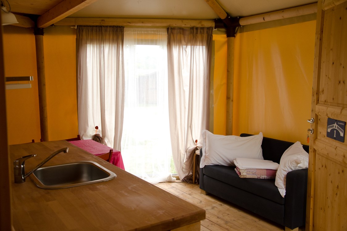 Glamping: Glamping-Zelte: Wohnzimmer mit Tisch, Stühlen, Spülbecken, Kühlschrank (ohne Küche) und Schlafsofa - Camping Rialto