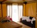 Glamping: Glamping-Zelte: Wohnzimmer mit Tisch, Stühlen, Spülbecken, Kühlschrank (ohne Küche) und Schlafsofa - Camping Rialto